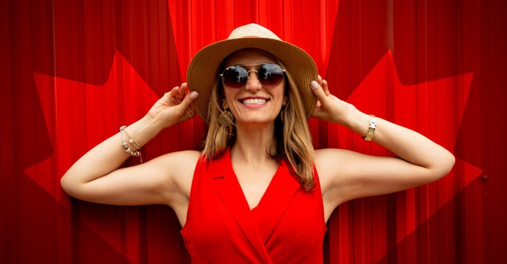A fashionable woman in a red dress and hat smiling proudly in front of a Canadian flag backdrop.