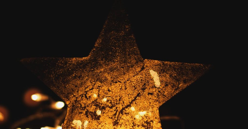 A shimmering golden star surrounded by warm Christmas string lights on a dark background. Perfect for holiday themes.