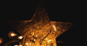 A shimmering golden star surrounded by warm Christmas string lights on a dark background. Perfect for holiday themes.