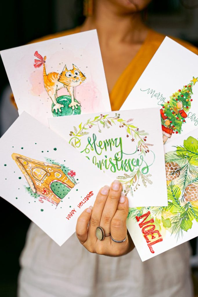 A collection of colorful Christmas cards held by a woman, featuring holiday-themed illustrations.