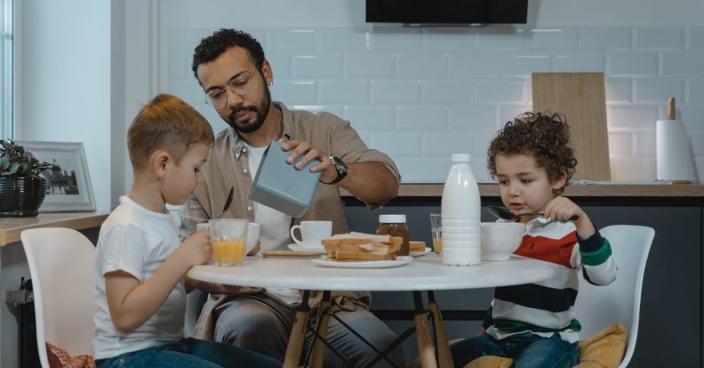 Father and sons enjoying breakfast together at a modern kitchen table.