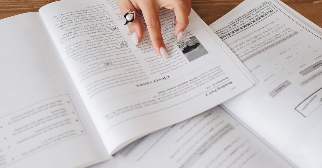 Hand resting on open books, creating a cozy study atmosphere.
