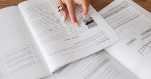 Hand resting on open books, creating a cozy study atmosphere.