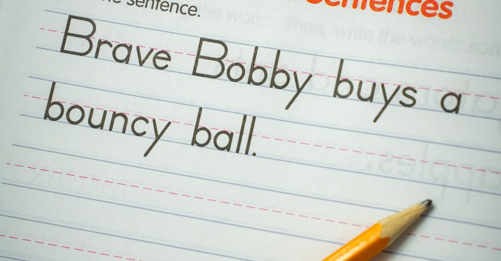 Writing sentence practice with a pencil on a lined workbook for elementary students.