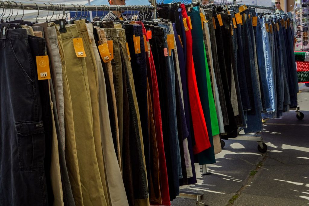 Vibrant collection of trousers showcasing various styles at a busy outdoor market stall.