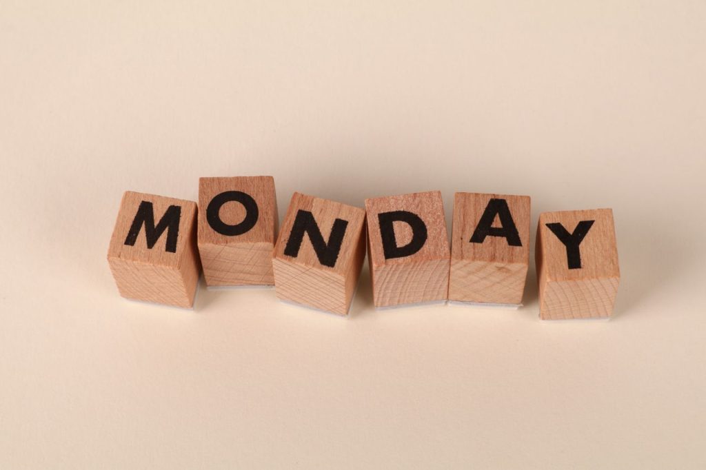 Wooden blocks spelling Monday on a neutral background, symbolic of the start of the week.