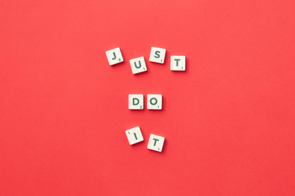 Motivational phrase 'Just Do It' spelled with Scrabble letters on a red background.