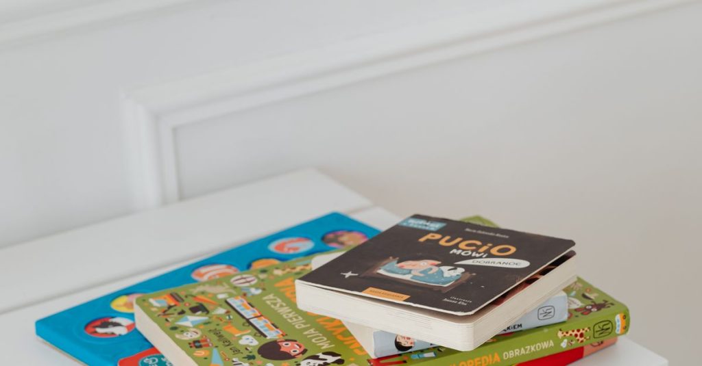 Vertical shot of children's books stacked on a white table in a bright space.
