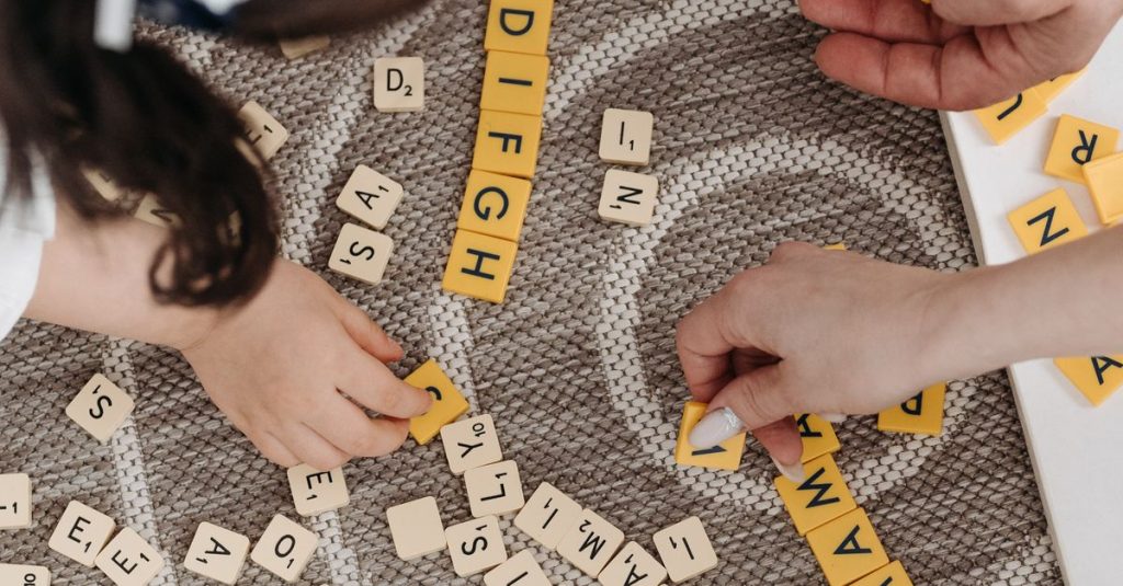Family playing a word game with tiles on a patterned carpet, showcasing togetherness and learning.