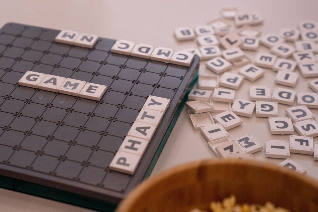 Scrabble board with scattered tiles spelling 'GAME', creating a playful, educational scene.