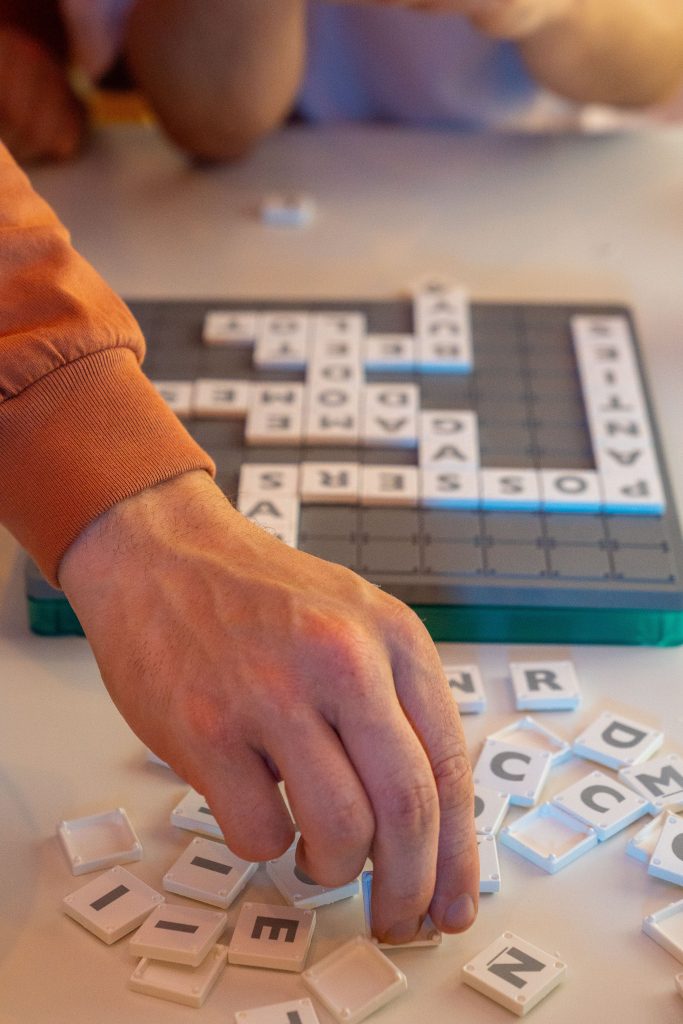 Hand placing Scrabble tiles on board during an engaging game session.