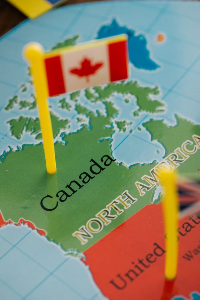 Detailed close-up of a Canadian flag standing on a map of North America, highlighting Canada.