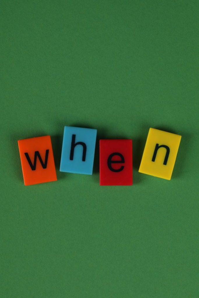 Four colorful alphabet tiles spelling 'when' on a green background, conveying curiosity.