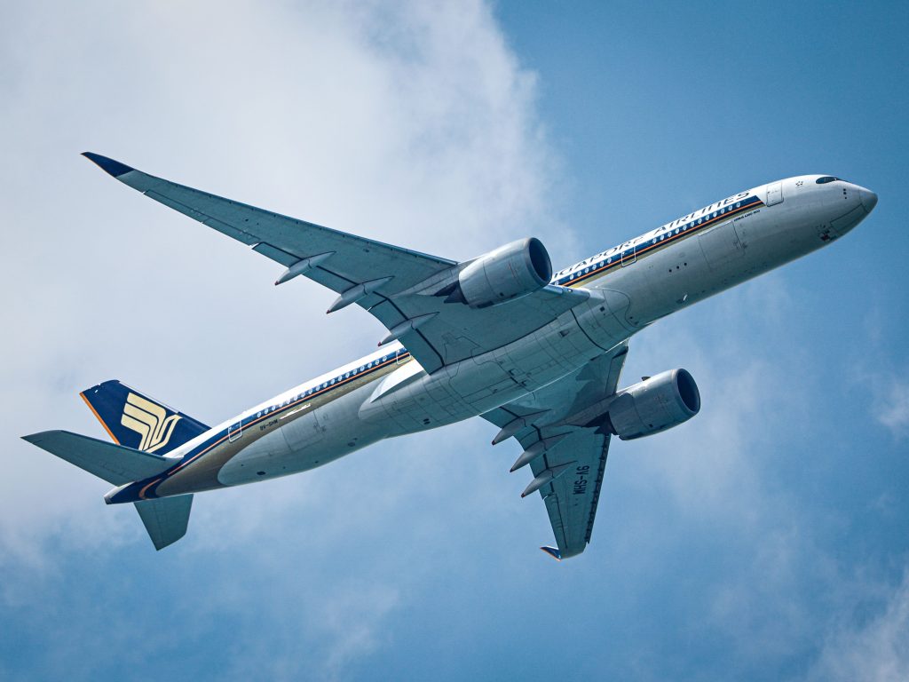 A commercial airliner soaring through a clear blue sky, viewed from below.
