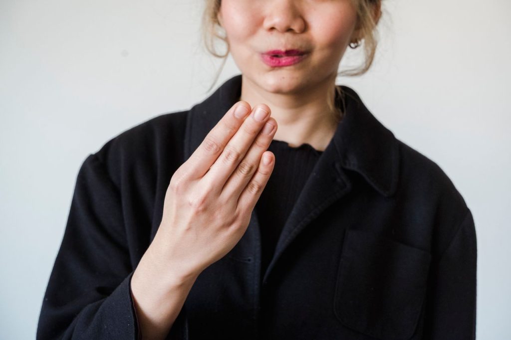 Close-up of a woman making a gesture with her hand against a white background. Ideal for communication themes.