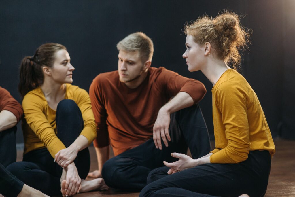 A group of young adults engaging in conversation, wearing casual yellow and brown.