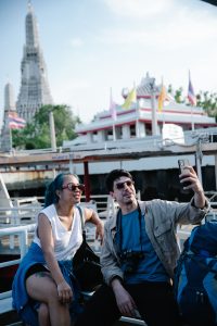 Travelers capturing moments at Wat Arun in Bangkok, enjoying cultural sightseeing.