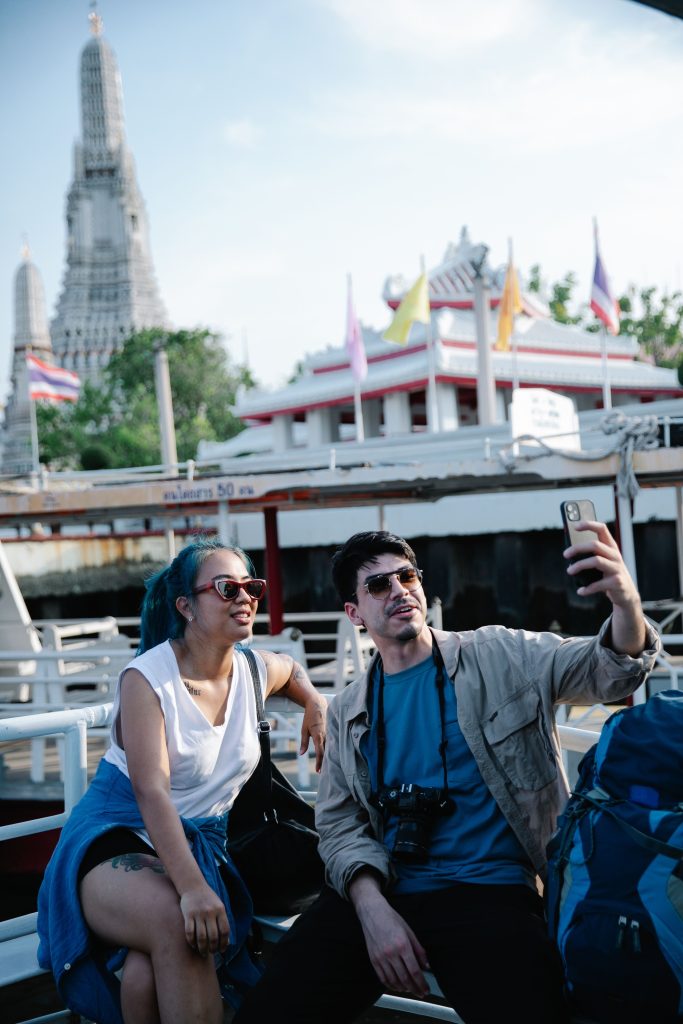 Travelers capturing moments at Wat Arun in Bangkok, enjoying cultural sightseeing.