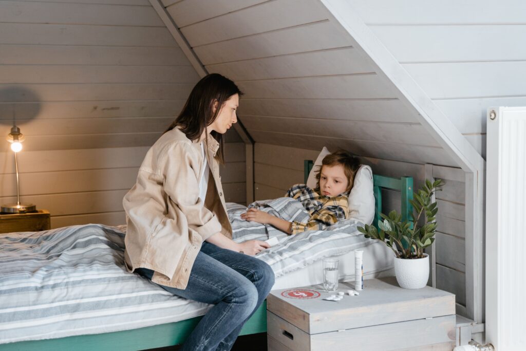 Mother gently caring for her sick child in a cozy bedroom setting, showing love and concern.